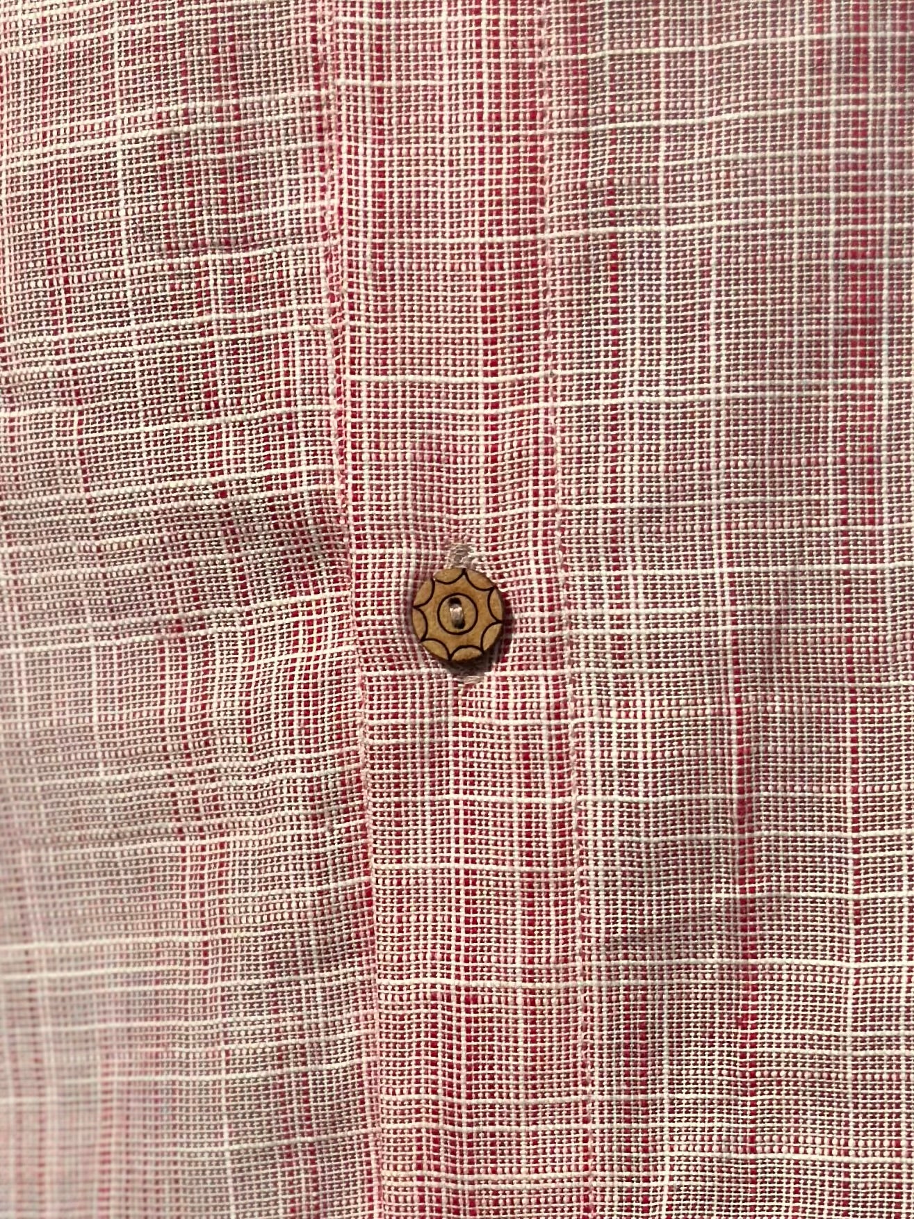 A close up photo of the designer coconut button with the intricate details of the fabric.