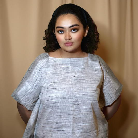 Woman wearing Surkh Amour’s handwoven cotton poncho top in natural beige, showcasing size-inclusive, sustainable fashion against a neutral backdrop.