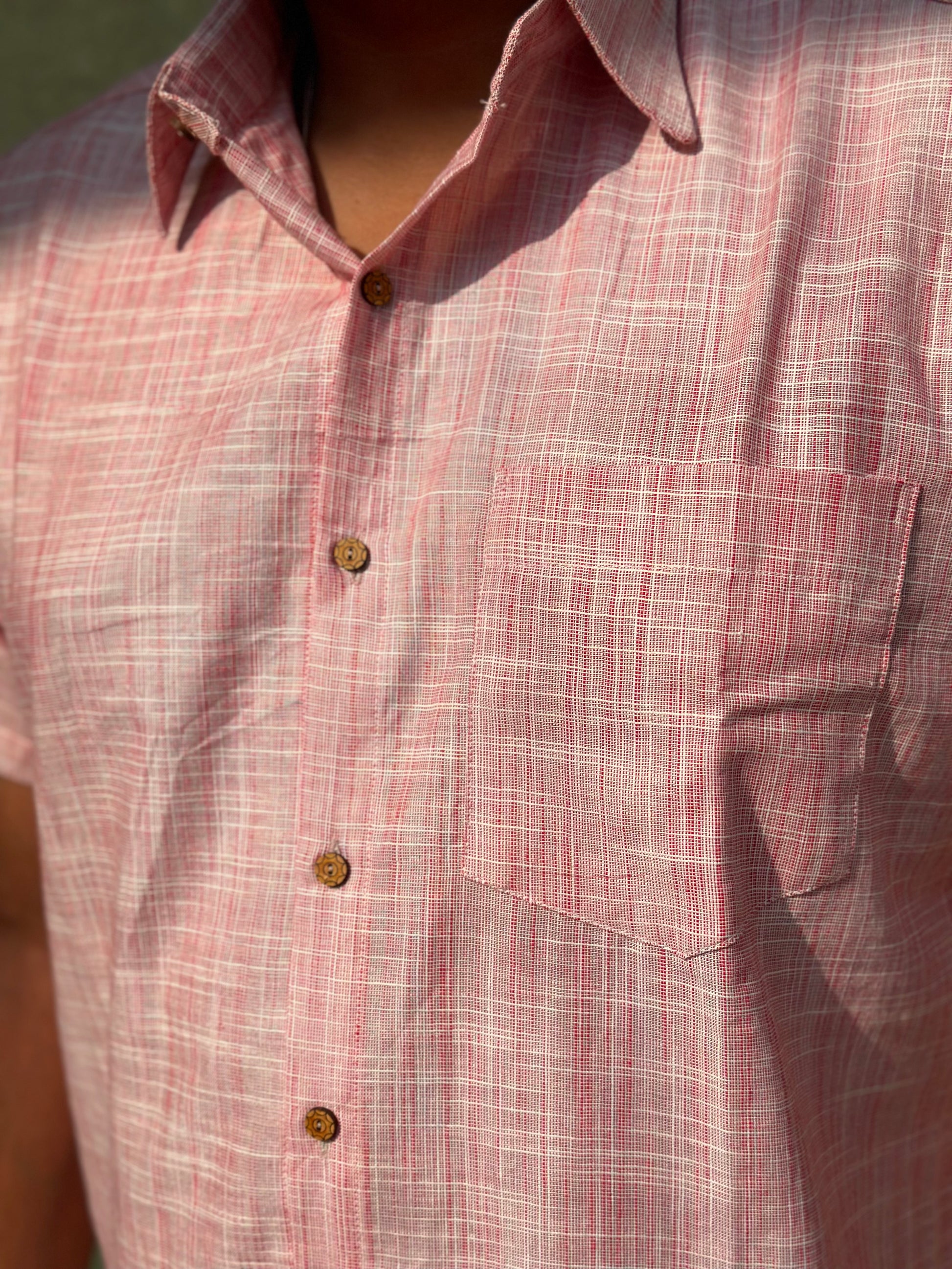A close up photo of the handmade khadi cotton shirt featuring a pocket and coconut buttons.